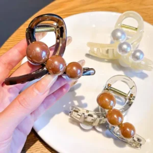 Pearl Hair Clips Set for Women Hand holding a pearl hair clip for women with two clips on a table.